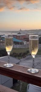 two glasses of wine sitting on a wooden table at 5 Cliff Street in Agulhas
