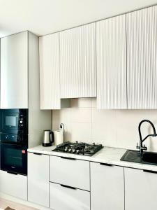 a kitchen with white cabinets and a stove top oven at 1 комнатные апартаменты in Atyraū +5 photos