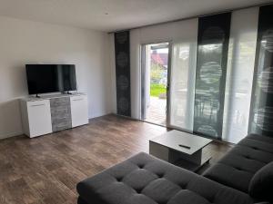 Una sala de estar con un sofá y un televisor de pantalla plana. en Ferienwohnung Innblick, en Marktl