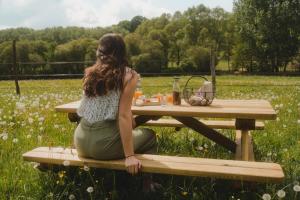 eine Frau, die an einem Picknicktisch auf einem Feld sitzt in der Unterkunft Parcel Tiny House I Elevage du Puits Carré in Dame-Marie