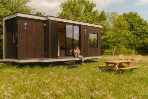 Eine Frau, die auf der Veranda eines winzigen Hauses sitzt. in der Unterkunft Parcel Tiny House I Elevage du Puits Carré in Dame-Marie