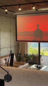 un grand écran avec un homme assis dessus dans un salon dans l'établissement Apartament Odlot, à Międzybrodzie Żywieckie