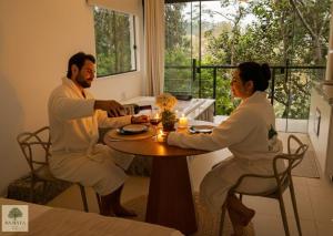 Ein Mann und eine Frau sitzen an einem Tisch in der Unterkunft DA MATA Chalés in Lindóia