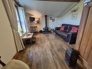 a living room with a leather couch and a fireplace at The Old Barn in Bettws Gwerfil Goch