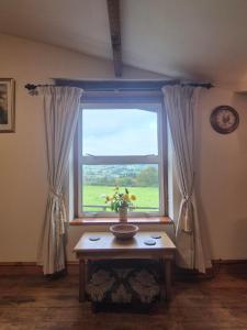 a window with a vase of flowers on a table at The Old Barn in Bettws Gwerfil Goch