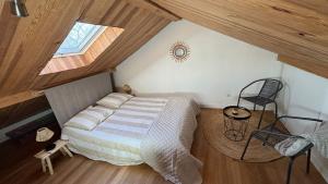 ein Schlafzimmer mit einem Bett und einem Stuhl auf einem Dachboden in der Unterkunft Maisonnette à la campagne in Roissard