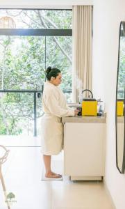 Eine Frau, die an einer Spüle in einer Küche steht. in der Unterkunft DA MATA Chalés in Lindóia