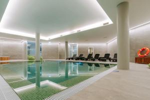 a swimming pool in a building with chairs around it at Hotel Euro Moniz in Porto Moniz
