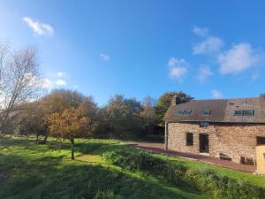 an old stone house in a field with trees at La Maison en Brocéliande in Paimpont