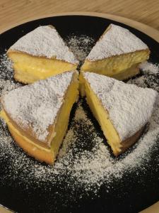 Dos rebanadas de pastel sobre un plato negro con azúcar glas en A Casa di Vale, en Nettuno
