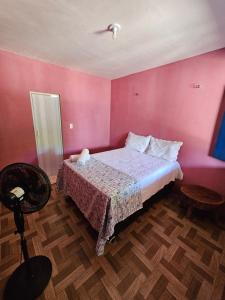 a bedroom with a bed and a pink wall at Pousada Brilho do Mar in Guriú
