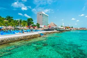 einen Strand mit Stühlen und Sonnenschirmen im Wasser in der Unterkunft El cid La ceiba beach in Cozumel + 3 Fotos