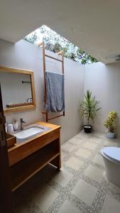 ein Badezimmer mit Waschbecken, Spiegel und Toilette in der Unterkunft SA Oeona Bungalow in Nembrala + 30 Fotos