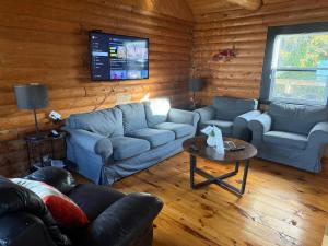 ein Wohnzimmer mit Sofas, einem Tisch und einem Fernseher in der Unterkunft Thanu Shack in Tobermory