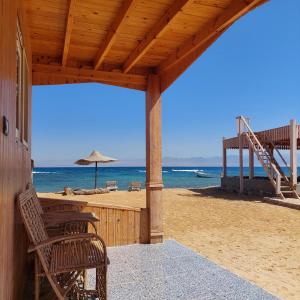 a porch of a beach with chairs and an umbrella at Shakazola Camp in Nuweiba