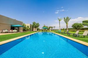 a swimming pool with blue water in a yard at Sublime villa, piscine chauffée, petit déjeuner inclus in Sehib Foukani