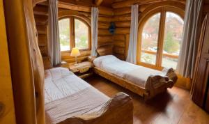 a bedroom with two beds in a log cabin at ROTUI CABAÑA EXCLUSIVA DON FERMIN in San Martín de los Andes +4 photos