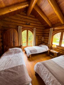 a bedroom with two beds in a log cabin at ROTUI CABAÑA EXCLUSIVA DON FERMIN in San Martín de los Andes