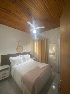 a bedroom with a large white bed with a wooden ceiling at Pousada Recanto da Vila in Pirenópolis