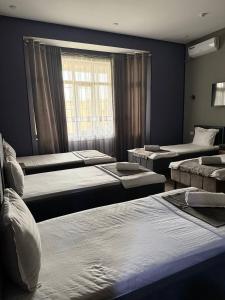 a room with three beds and a window at Nari 2 Hotel in Toshkent-Passajir Bekati