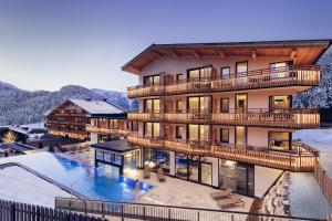 a building with a swimming pool in the snow at Hotel habicher hof - Your 4-Star Superior Wellness Hideaway in Oetz
