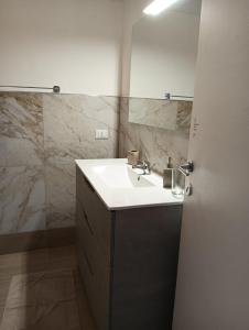 baño con lavabo blanco y paredes de mármol en Wendy's House- self check in-, en Bérgamo