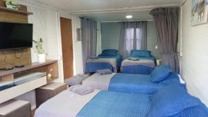 a room with four beds and a flat screen tv at Habitaciones Barrancas en San Antonio - Cabañas y Mini Departamentos in San Antonio