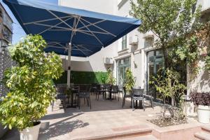 un patio con sombrilla azul, mesas y sillas en Hotel Liqeni, en Tirana
