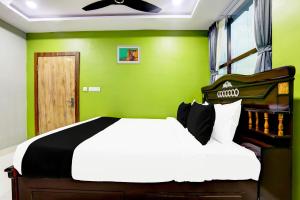 a bedroom with a bed and a green wall at Hotel O Savoy Grand in Warangal