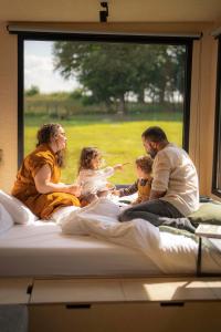 a group of people sitting on a bed in a window at Parcel Tiny House I L'Arche des Hays in Les Hays