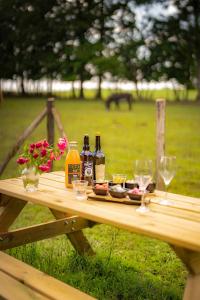a picnic table with wine bottles and glasses on it at Parcel Tiny House I L'Arche des Hays in Les Hays +11 photos