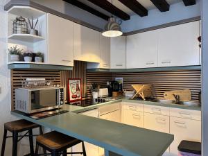 a kitchen with white cabinets and a counter with a microwave at Le Charmant Zola Hyper Centre classé in Troyes