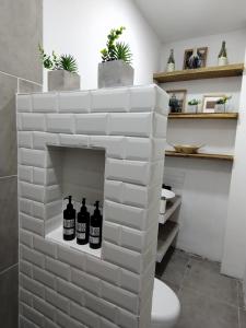 Una pared de ladrillo blanco con tres botellas en un baño en La Casa de Nelly - Medellín, en Medellín 30 fotos más