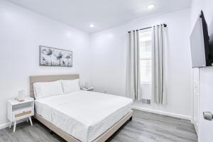 a white bedroom with a bed and a window at Newly Built Lake House Near NYC EWR MetLife AD Mall in Passaic