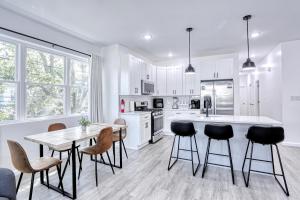 a kitchen with white cabinets and a table and chairs at Newly Built Lake House Near NYC EWR MetLife AD Mall in Passaic