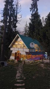 a large building with a blue roof in a forest at The shire kalga in Kasol