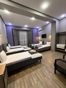 a room with three beds and a tv at Nari 2 Hotel in Toshkent-Passajir Bekati