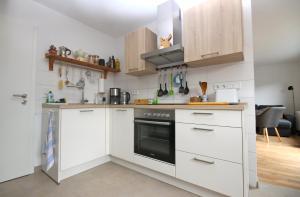 a kitchen with white cabinets and a black oven at ÜbermTal in Schmallenberg