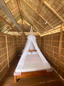 a bed in a bamboo room with a mosquito net at Batanta Guest House in Pulau Birie