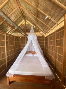 a bed in a bamboo room with a mosquito net at Batanta Guest House in Pulau Birie +23 photos