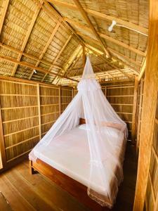 a bed in a room with a mosquito net at Batanta Guest House in Pulau Birie