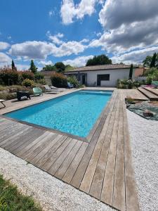 a swimming pool with a wooden deck and a house at Le Cocon de Pinerato in Albi