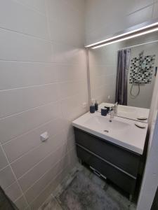 a white bathroom with a sink and a mirror at Le Cocon de Pinerato in Albi