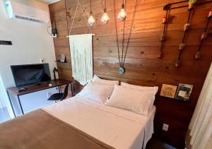 a bedroom with a bed and a desk and a television at Éden Bed & Nature in Praia Grande
