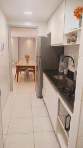 a kitchen with white cabinets and a table with a dining room at Apartamento Aconchegante e completo em Manaíra in João Pessoa