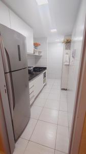 a white kitchen with a stainless steel refrigerator at Apartamento Aconchegante e completo em Manaíra in João Pessoa