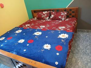 ein Bett mit einer blauen Bettdecke mit Blumen darauf in der Unterkunft Blueocean Residency in Virāmpattinam