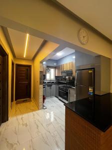 a kitchen with a black counter and a clock on the wall at First 6th October Compound of Degla Gardens Comfort in ‘Ezbet `Abd el-Ḥamîd
