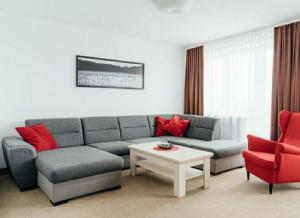 a living room with a gray couch and red chairs at Jedno 17 aparts in Wrocław
