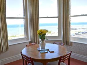 een eetkamer met een tafel met een vaas met bloemen bij Bounty in Cromer